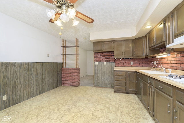 kitchen with sink, a textured ceiling, wooden walls, and backsplash