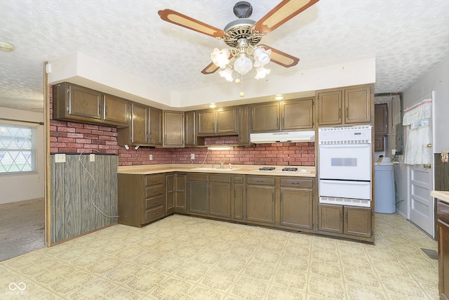 kitchen featuring a textured ceiling, tasteful backsplash, and white appliances