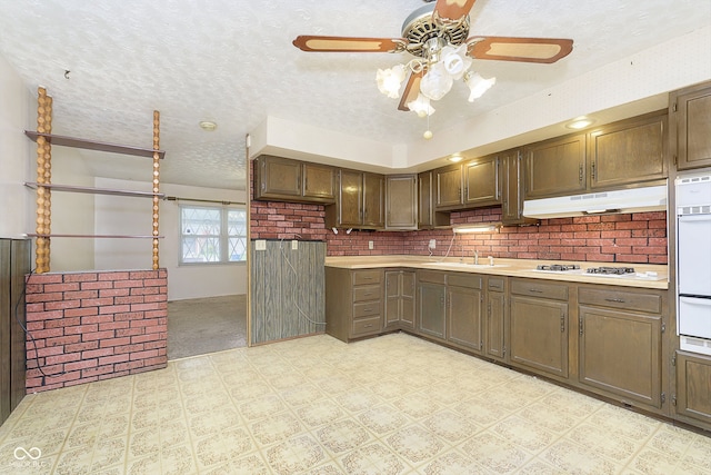 kitchen featuring ceiling fan, sink, backsplash, a textured ceiling, and white appliances