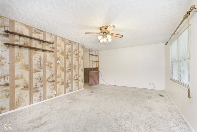 carpeted empty room with ceiling fan and a textured ceiling