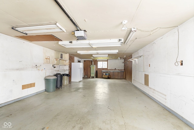 garage featuring a workshop area, white refrigerator, a garage door opener, and fridge