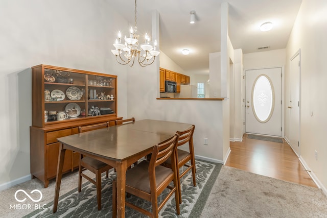 dining room featuring a notable chandelier, lofted ceiling, and light hardwood / wood-style flooring