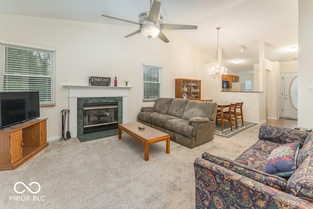 carpeted living room with a fireplace, ceiling fan with notable chandelier, and vaulted ceiling