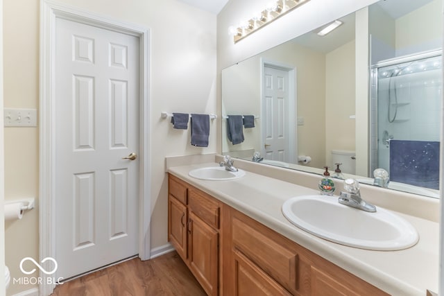 bathroom with hardwood / wood-style floors, vanity, toilet, and an enclosed shower