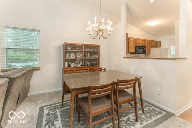 dining space with an inviting chandelier, light colored carpet, and vaulted ceiling