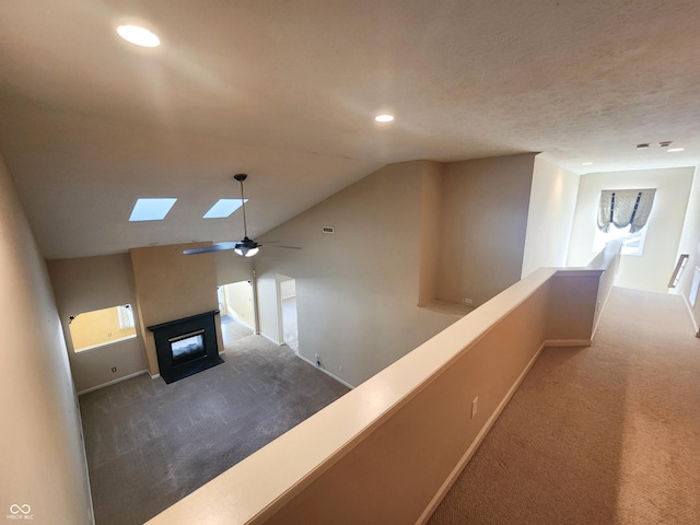 hallway with lofted ceiling with skylight and carpet