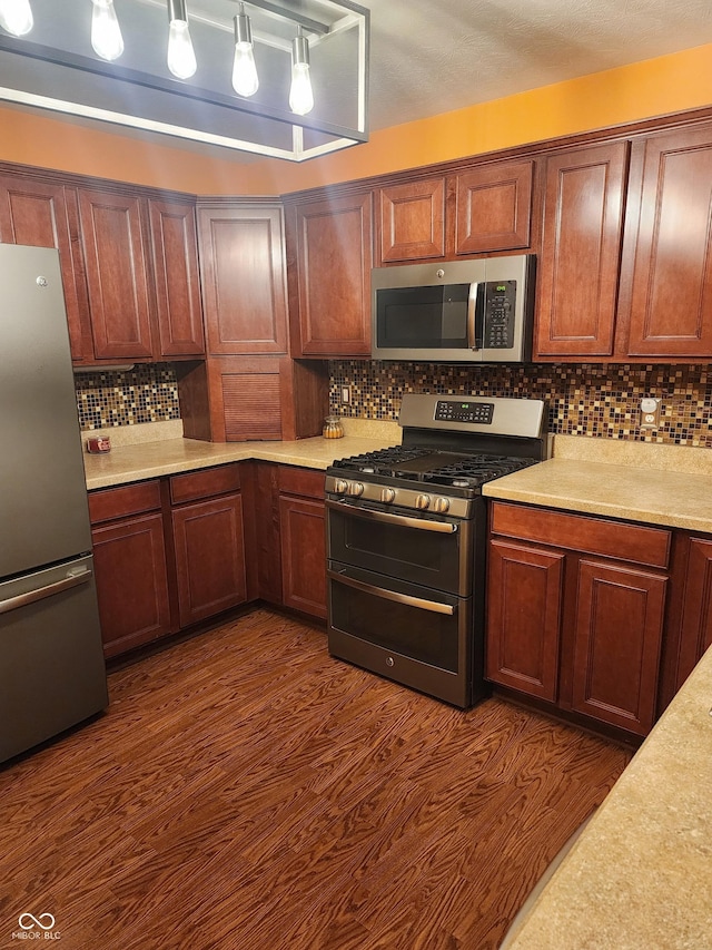 kitchen with tasteful backsplash, stainless steel appliances, dark hardwood / wood-style flooring, and hanging light fixtures