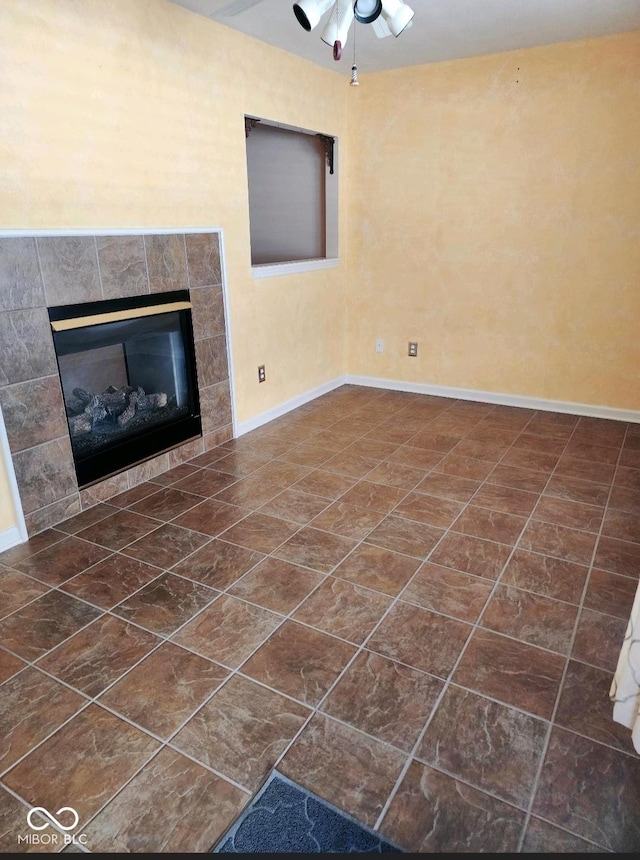 unfurnished living room featuring dark tile patterned floors, a fireplace, and ceiling fan