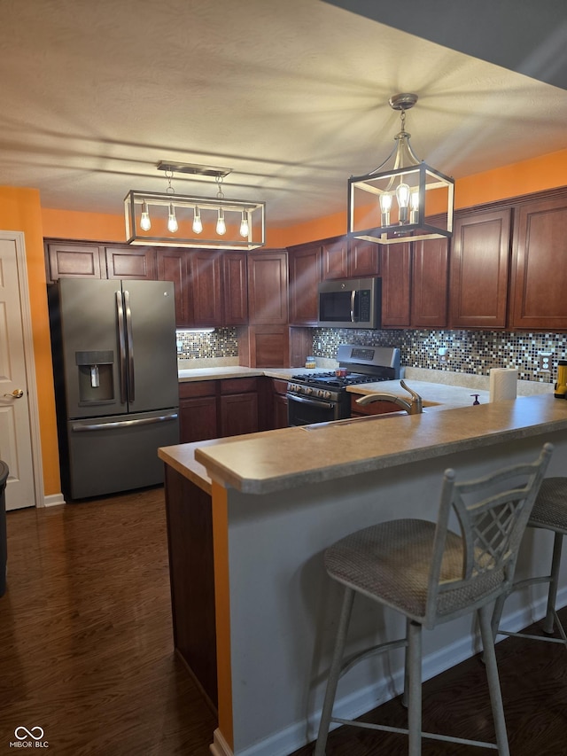 4835 Franklin Villas Dr, Indianapolis, IN 46237 - kitchen featuring stainless steel appliances, a peninsula, decorative backsplash, pendant lighting, and light countertops