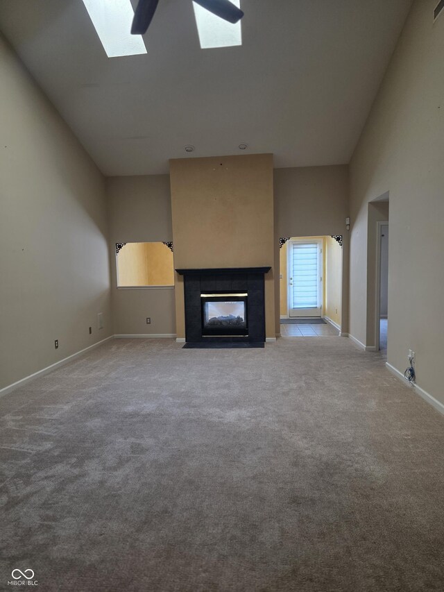 4835 Franklin Villas Dr, Indianapolis, IN 46237 - unfurnished living room featuring carpet, a tile fireplace, a skylight, and a high ceiling