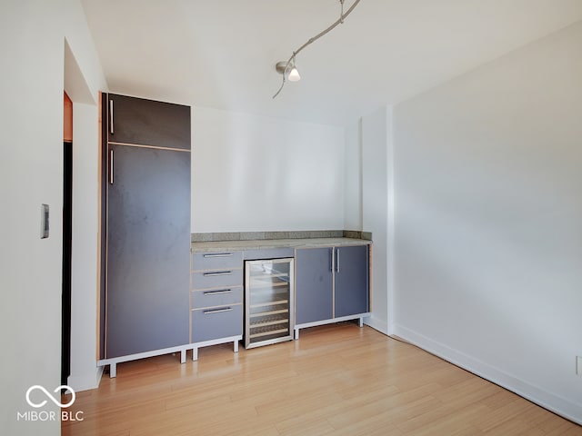 interior space with bar area, beverage cooler, and light wood-type flooring