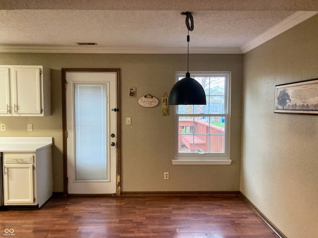 unfurnished dining area featuring a textured ceiling, dark hardwood / wood-style floors, and crown molding