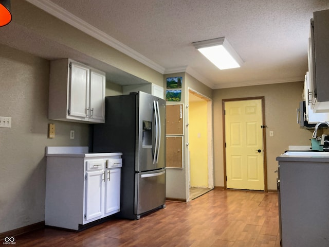 kitchen featuring stainless steel refrigerator with ice dispenser, a textured ceiling, crown molding, light hardwood / wood-style flooring, and white cabinets