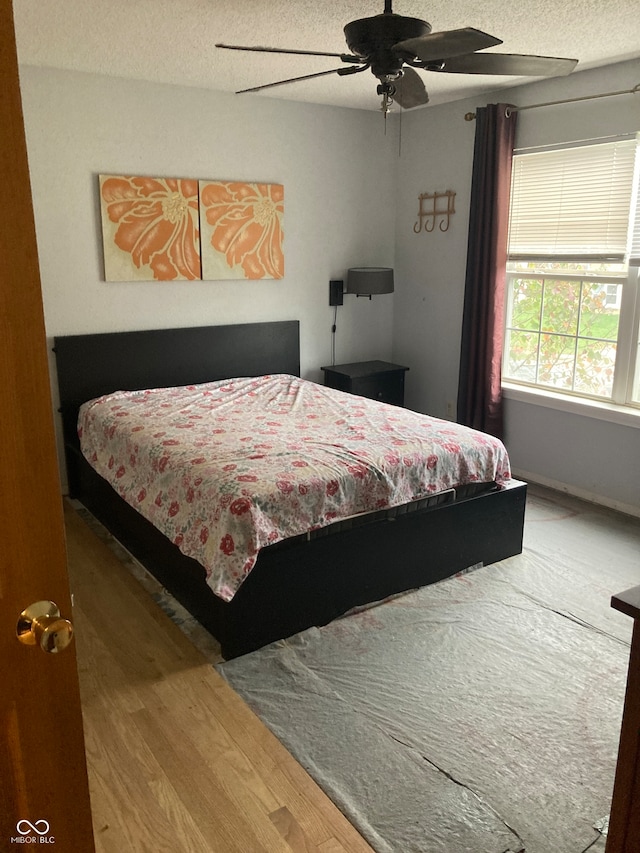 bedroom featuring hardwood / wood-style floors, a textured ceiling, and ceiling fan