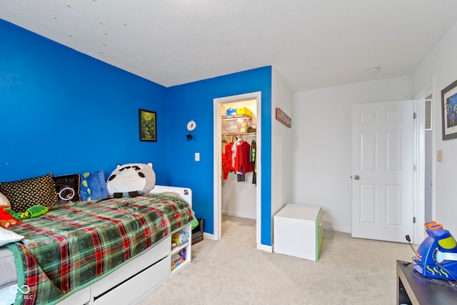 bedroom featuring light carpet, a spacious closet, and a closet