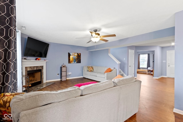 living room with ceiling fan, a high end fireplace, and hardwood / wood-style flooring