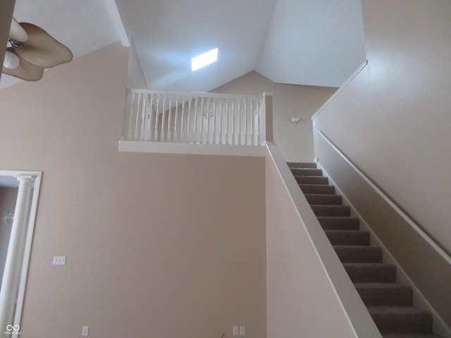 staircase featuring ceiling fan and vaulted ceiling with skylight