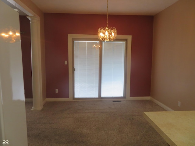 unfurnished dining area with carpet floors, decorative columns, and an inviting chandelier