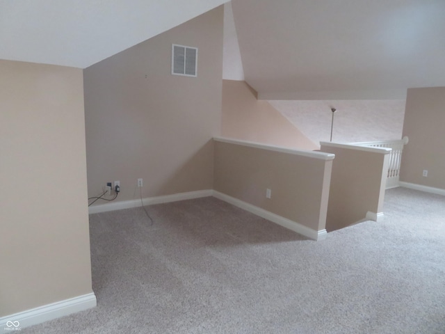 additional living space with light colored carpet and vaulted ceiling