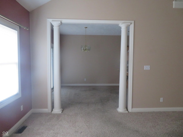 unfurnished room featuring a notable chandelier, plenty of natural light, light carpet, and vaulted ceiling