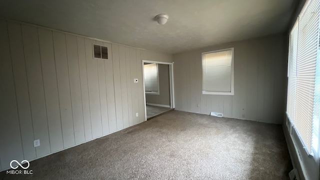 unfurnished bedroom with carpet floors and wood walls