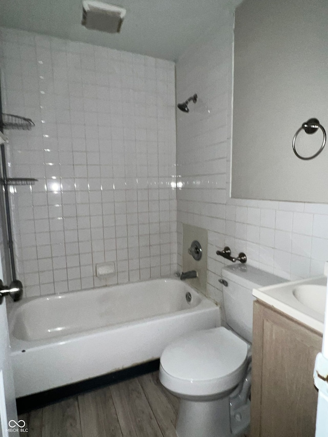 full bathroom with vanity, hardwood / wood-style flooring, tile walls, toilet, and tiled shower / bath