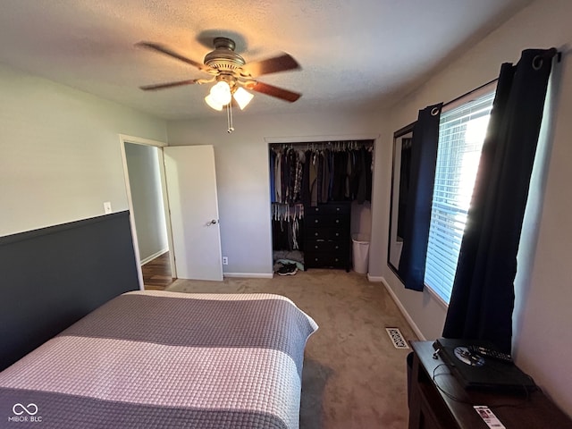 carpeted bedroom with ceiling fan, a textured ceiling, and a closet