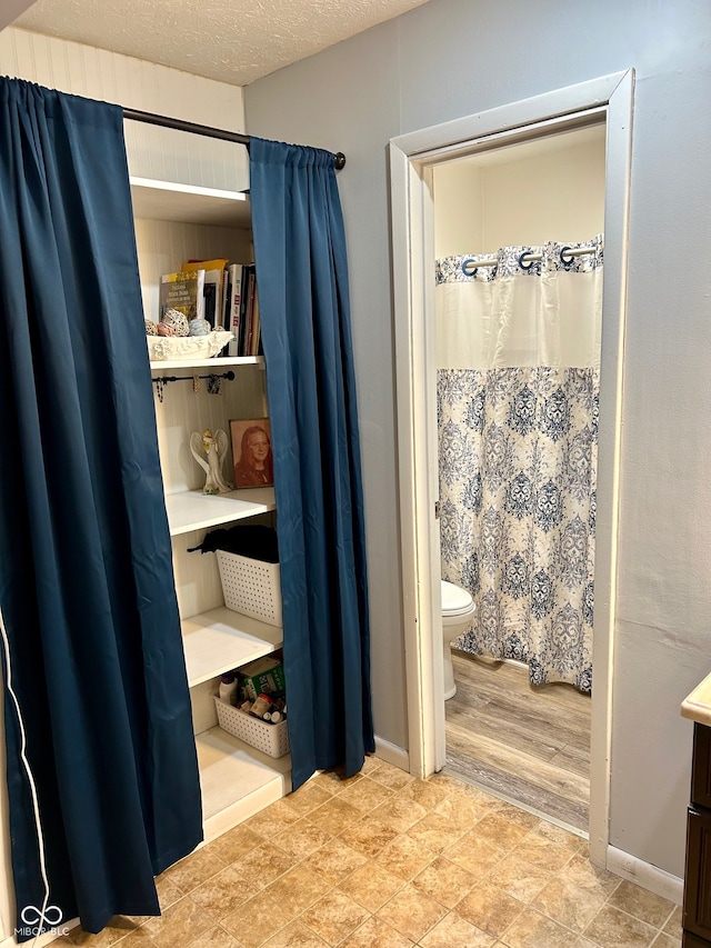 bathroom with hardwood / wood-style flooring, vanity, toilet, and a textured ceiling