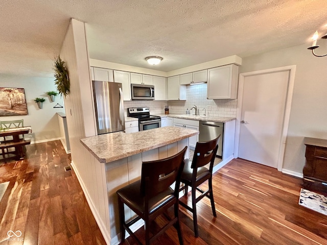 kitchen featuring a textured ceiling, a breakfast bar, dark hardwood / wood-style flooring, and stainless steel appliances