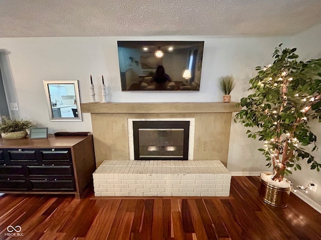 interior space featuring dark wood-type flooring, a textured ceiling, and a brick fireplace