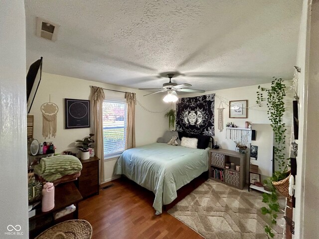 bedroom with ceiling fan, wood-type flooring, and a textured ceiling