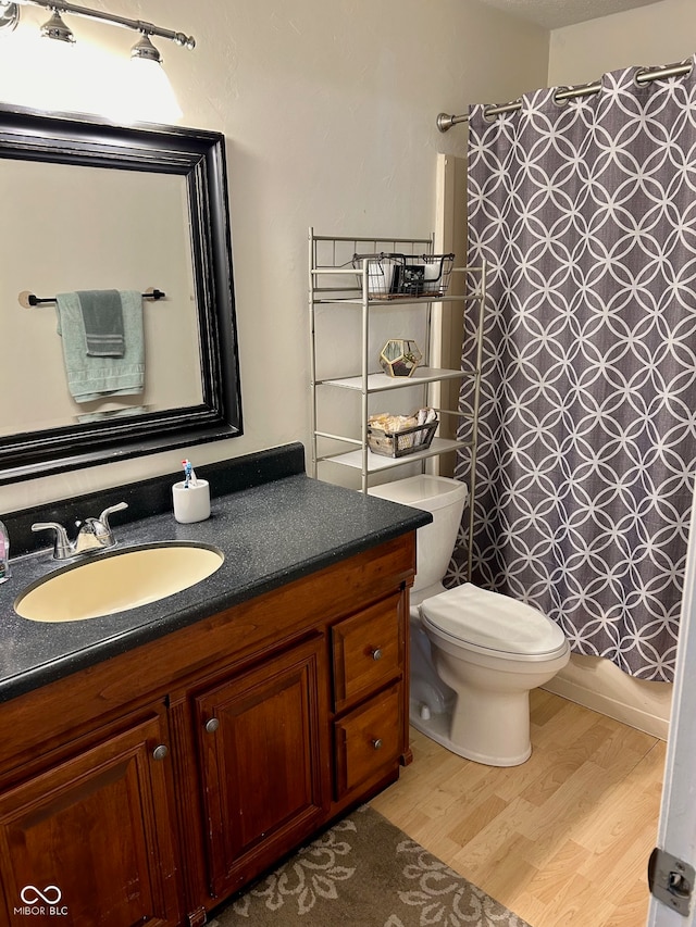 full bathroom featuring hardwood / wood-style flooring, vanity, toilet, and shower / tub combo