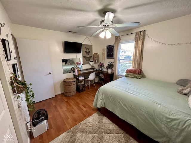 bedroom with ceiling fan, wood-type flooring, and a textured ceiling