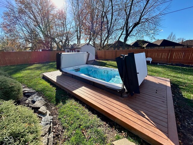 view of swimming pool with a wooden deck, a lawn, and an outdoor hot tub