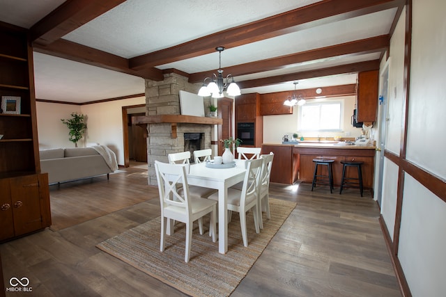 dining area with dark wood-type flooring, beamed ceiling, a notable chandelier, a textured ceiling, and a fireplace