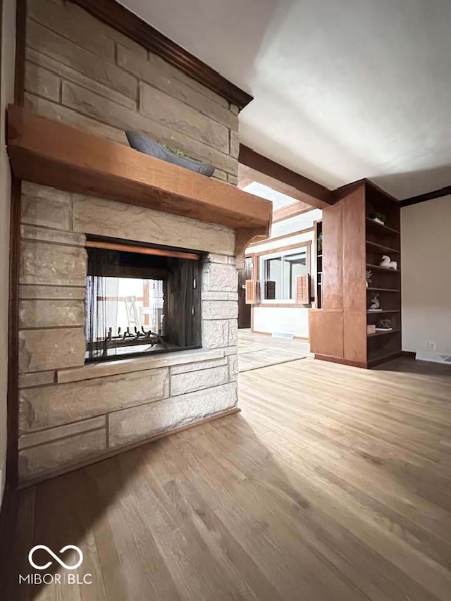 unfurnished living room with hardwood / wood-style flooring, beam ceiling, and a fireplace