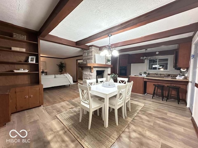 dining space featuring beamed ceiling, wood-type flooring, and a textured ceiling