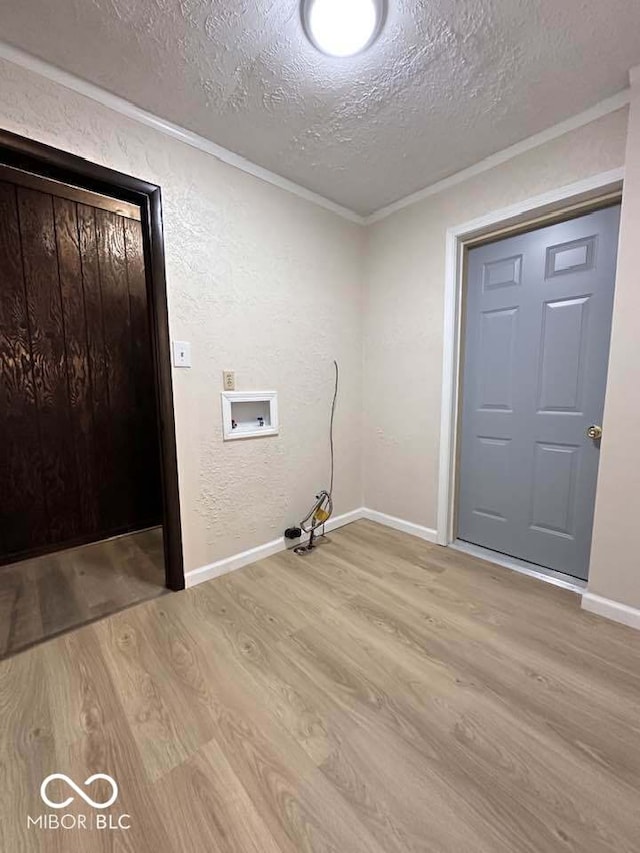 clothes washing area featuring crown molding, hookup for a washing machine, a textured ceiling, and light wood-type flooring