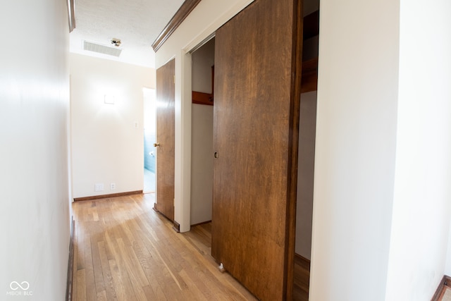 hall with light hardwood / wood-style flooring and a textured ceiling