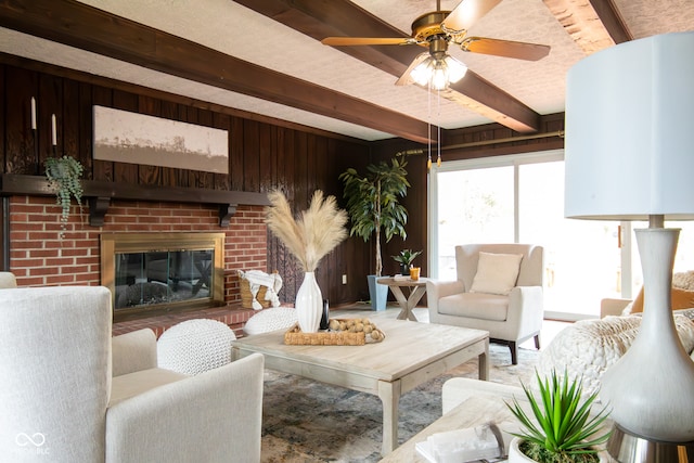 living room with beamed ceiling, a brick fireplace, ceiling fan, and wooden walls