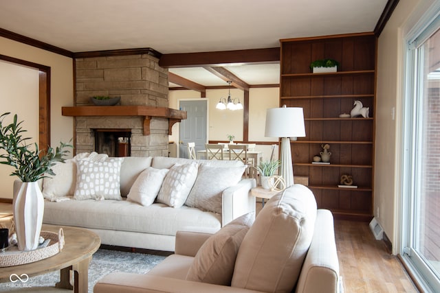 living room with a stone fireplace, beamed ceiling, a notable chandelier, crown molding, and light hardwood / wood-style floors