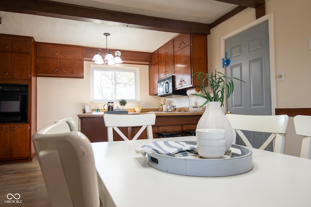 dining space with beam ceiling, hardwood / wood-style floors, and a notable chandelier