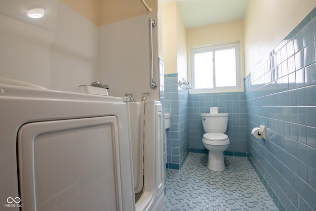 bathroom featuring tile patterned flooring, washer / clothes dryer, toilet, and tile walls