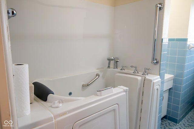 bathroom featuring tile patterned floors, a bathing tub, and tile walls