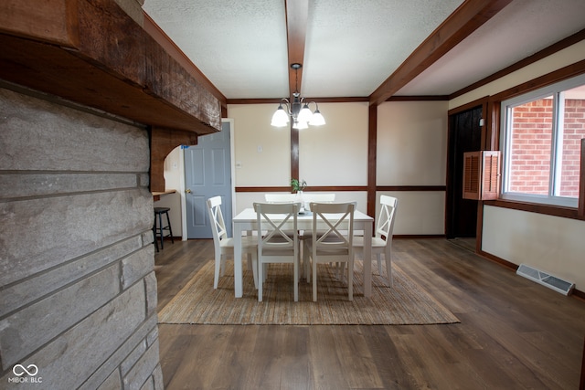 unfurnished dining area featuring dark hardwood / wood-style flooring, ornamental molding, a textured ceiling, and a chandelier