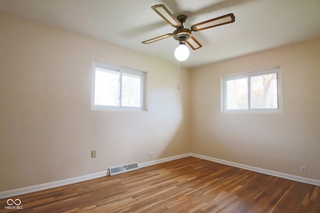 unfurnished room featuring plenty of natural light, ceiling fan, and dark hardwood / wood-style flooring