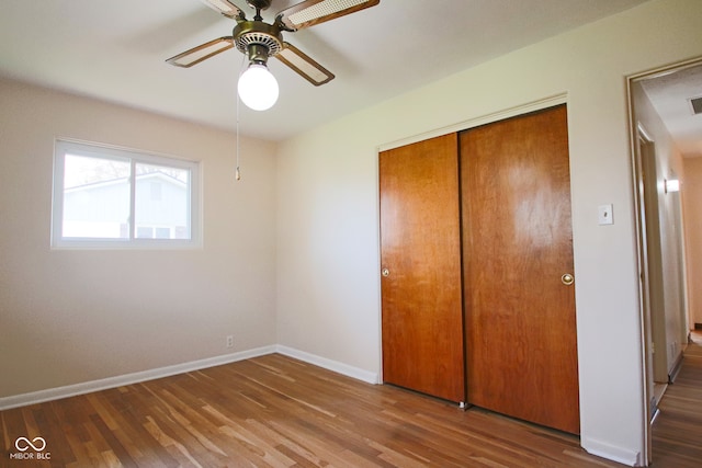 unfurnished bedroom featuring ceiling fan, a closet, and wood-type flooring