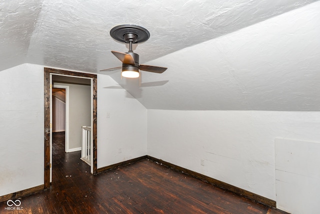 additional living space featuring a textured ceiling, ceiling fan, lofted ceiling, and dark wood-type flooring