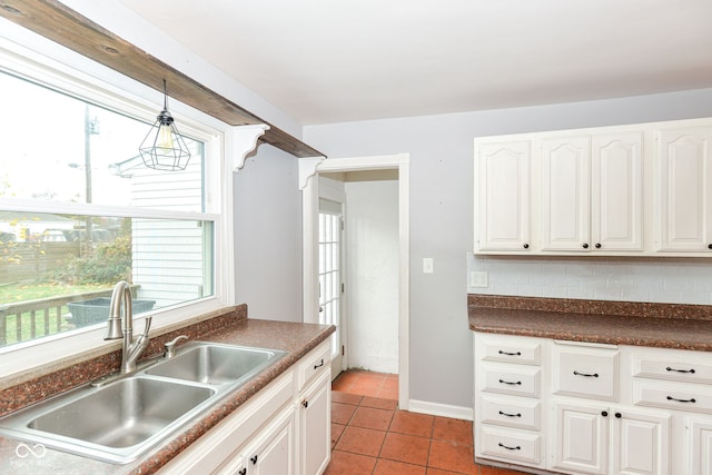 kitchen featuring light tile patterned floors, decorative light fixtures, white cabinetry, and sink