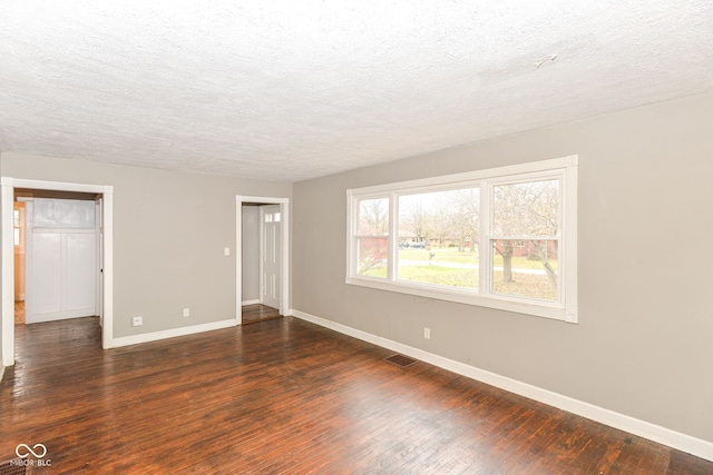 spare room with dark hardwood / wood-style floors and a textured ceiling